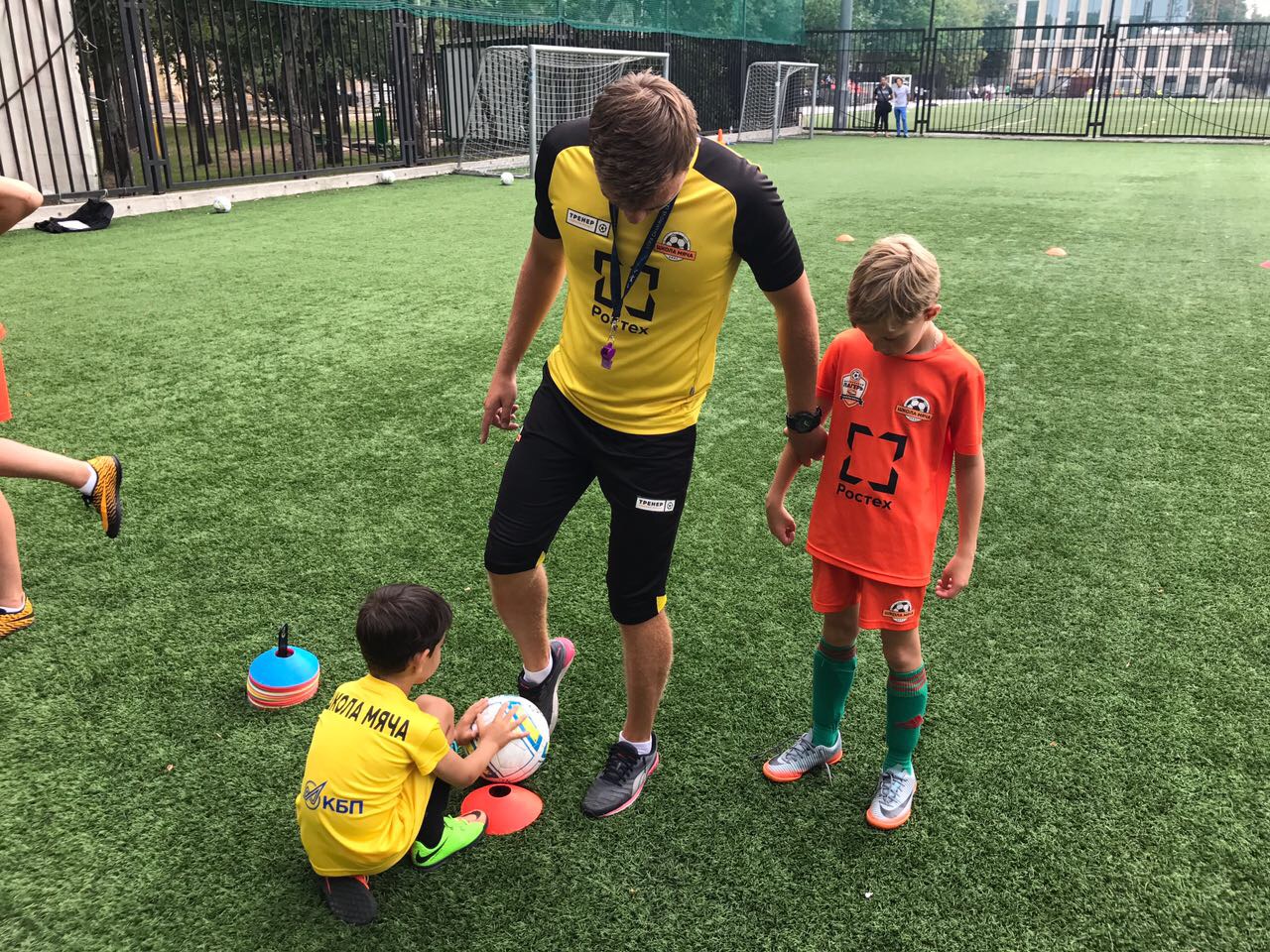 Детский футбольный тренер показывает как выполнять технический прием с футбольным мячем детям