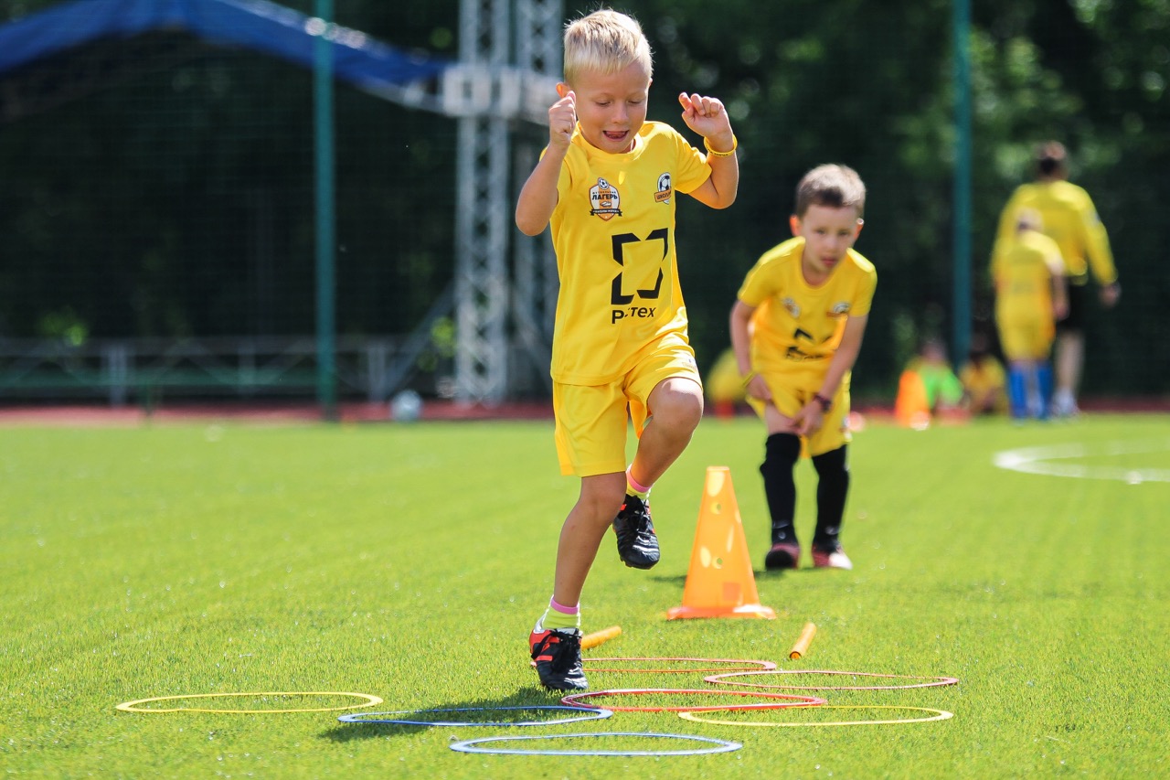 Счастливый ребенок-футболист тренируется на футбольном поле
