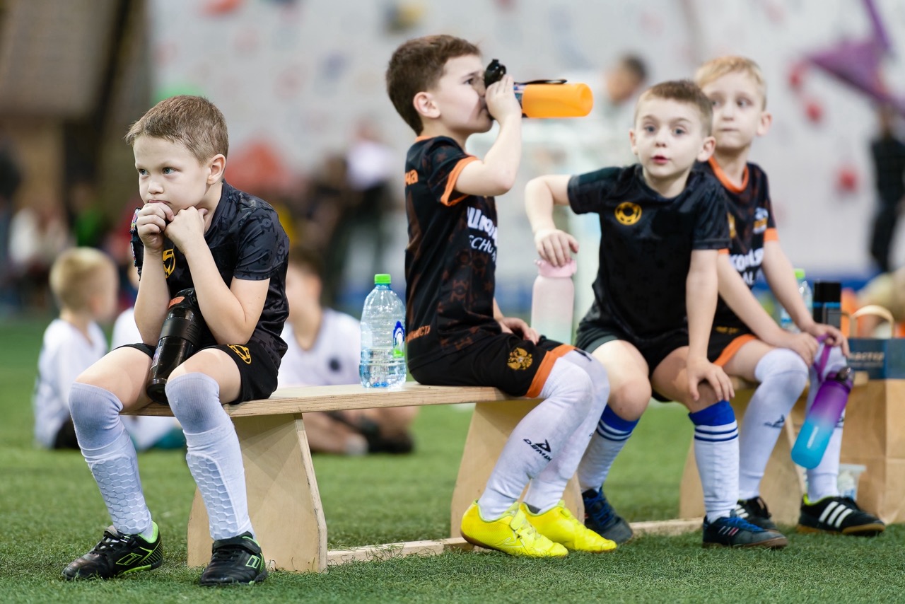 Футболисты Школы мяча отдыхают на скамейке после матча на турнире